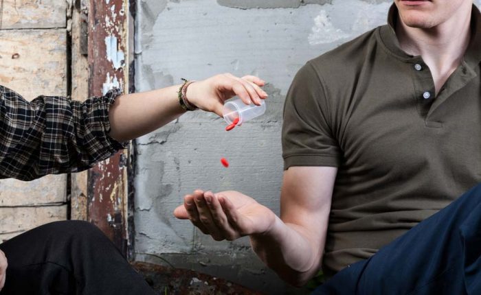picture of one young adult giving prescription drugs to another - acceptance of drugs in our culture - Fair Oaks Recovery Center of california - sacramento california drug rehab center - drug and alcohol addiction treatment and detox center