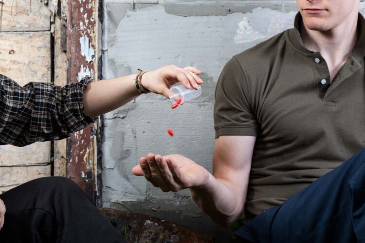 picture of one young adult giving prescription drugs to another - acceptance of drugs in our culture - Fair Oaks Recovery Center of california - sacramento california drug rehab center - drug and alcohol addiction treatment and detox center