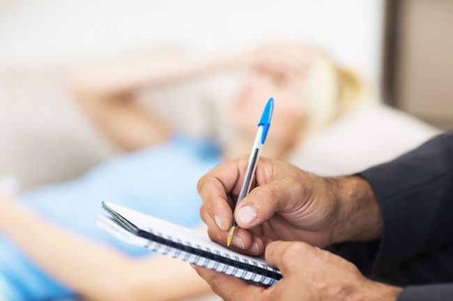 therapist taking notes while patient lies on couch - dual diagnosis treatment