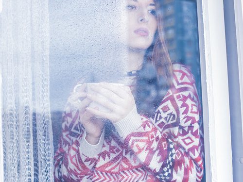 Natural Remedies for the Winter Blues - woman looking out at the snow