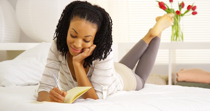 Journaling for Emotional Awareness - woman laying on bed writing in journal