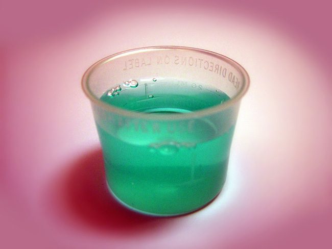medicine cup of green liquid - medications