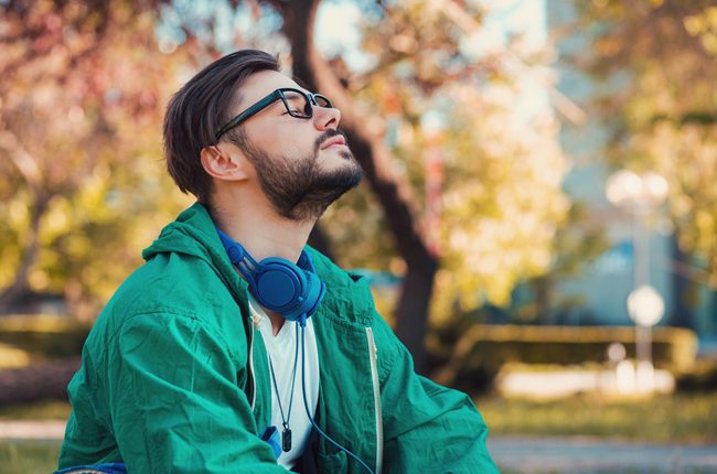 how to treat mental illness without medication, brunette bearded man with glasses in green coat taking deep breath outdoors - mental health