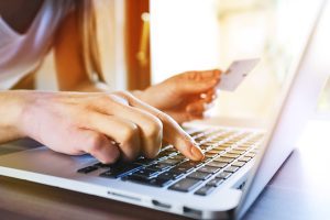 closeup of woman entering credit care info into laptop - cross addiction