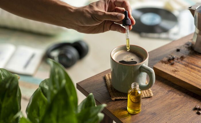a person dropping CBD oil into their coffee