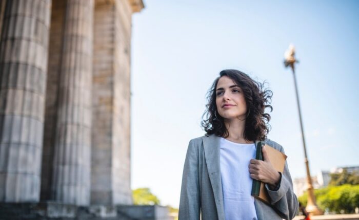 Fair Oaks - Use Emotional Regulation to Your Advantage. A woman stands outside a professional building in professional attire. She appears well regulated as she stares into the distance.